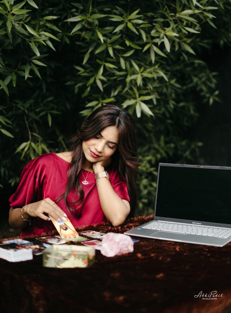 Vedika at a tarot table with laptop for online sessions